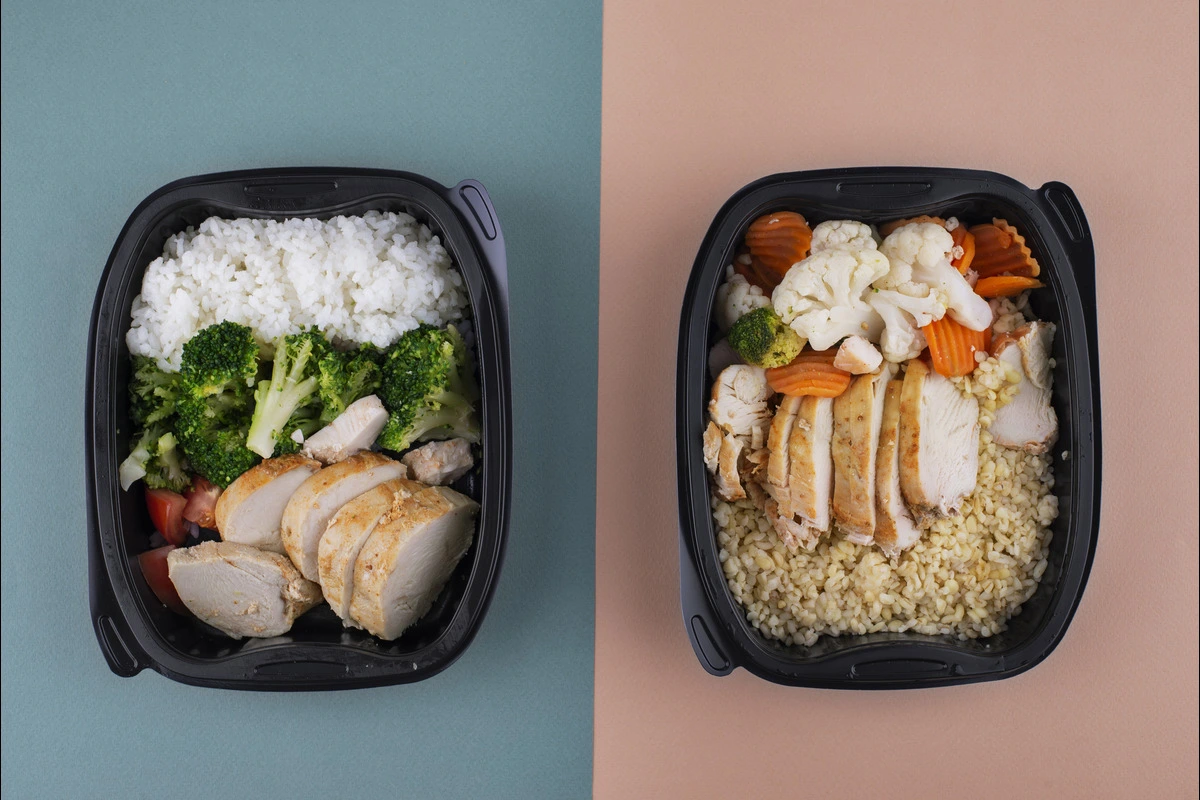 Colorful and nutritious bento box filled with rice, grilled chicken, vegetables, and fruits arranged in a partitioned container.