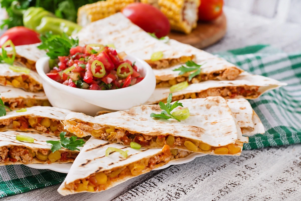 Chicken quesadillas with melted cheese, vegetables, and garnishes